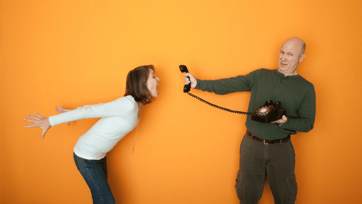 Man holds telephone while angry woman shouts into it