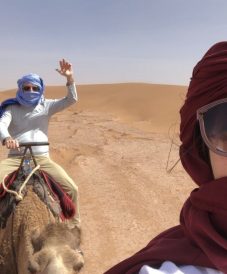 a couple in the desert riding camels