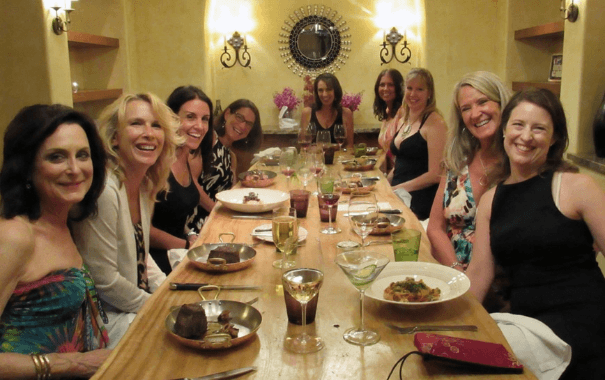 group of beautiful women sitting around dinner table smiling to the camera