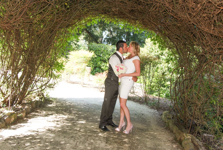 newly-wed couple kissing under an arc of dried stems