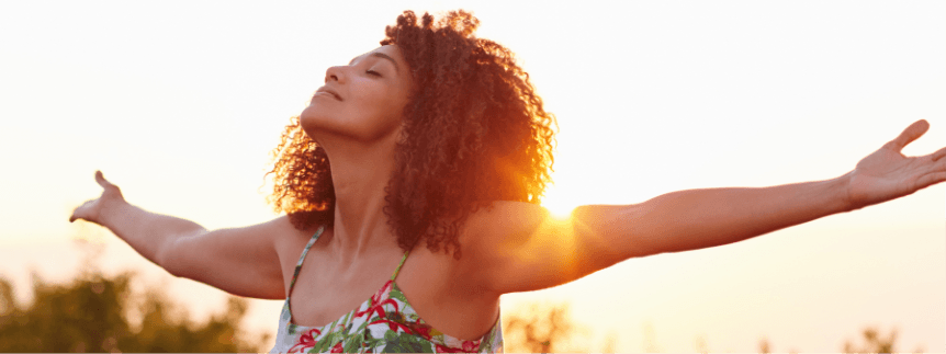 woman extending her arms while eyes are closed and smiling