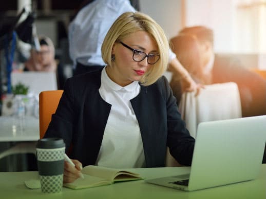 young, businesswoman working on her laptop while analyzing documents